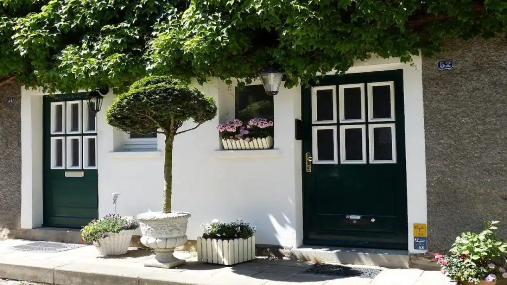 Porte d’entrée et volets en bois poncés et repeints sur une façade de maison rénovée, avec marquise en fer forgé